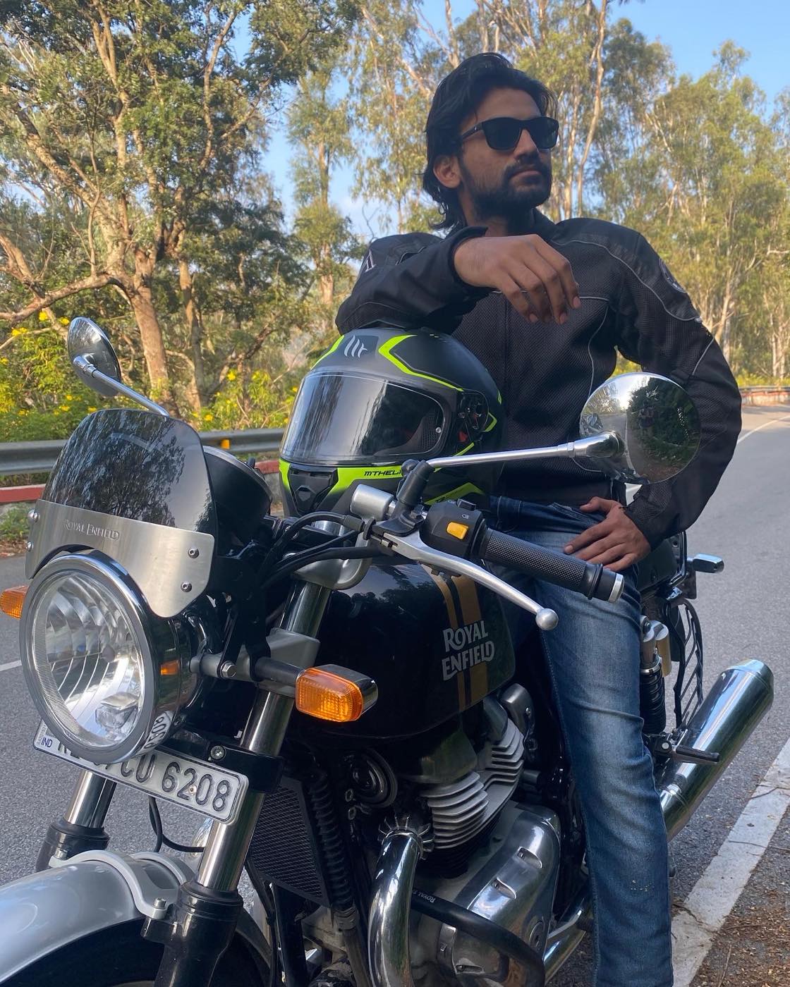 On a Royal Enfield Interceptor on a tree-lined hill road